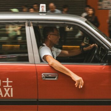 Man driving a red taxi in a city